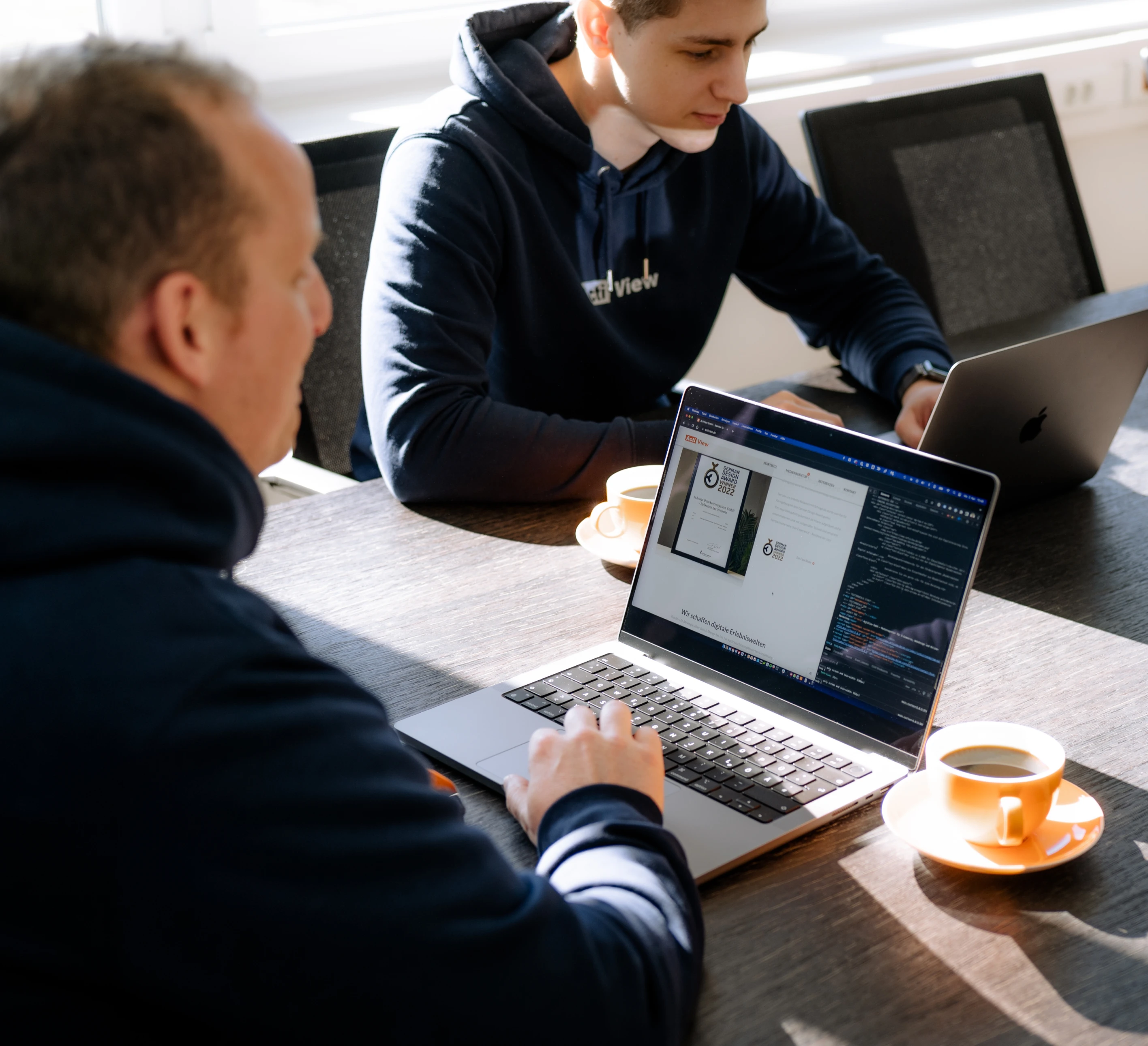 Zwei Mitarbeiter arbeiten gemeinsam an einem Projekt im Besprechnungsraum