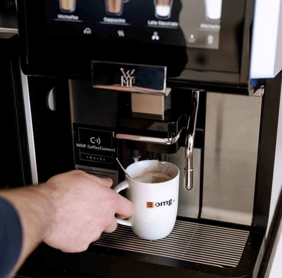 Mitarbeiter zapft sich an der Kaffeemaschine einen Kaffee.