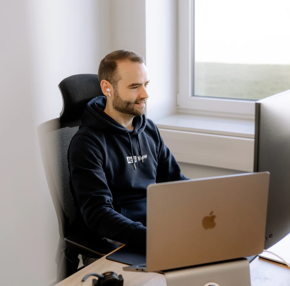 Ein Webdesigner im Online-Meeting am hellen Arbeitsplatz.