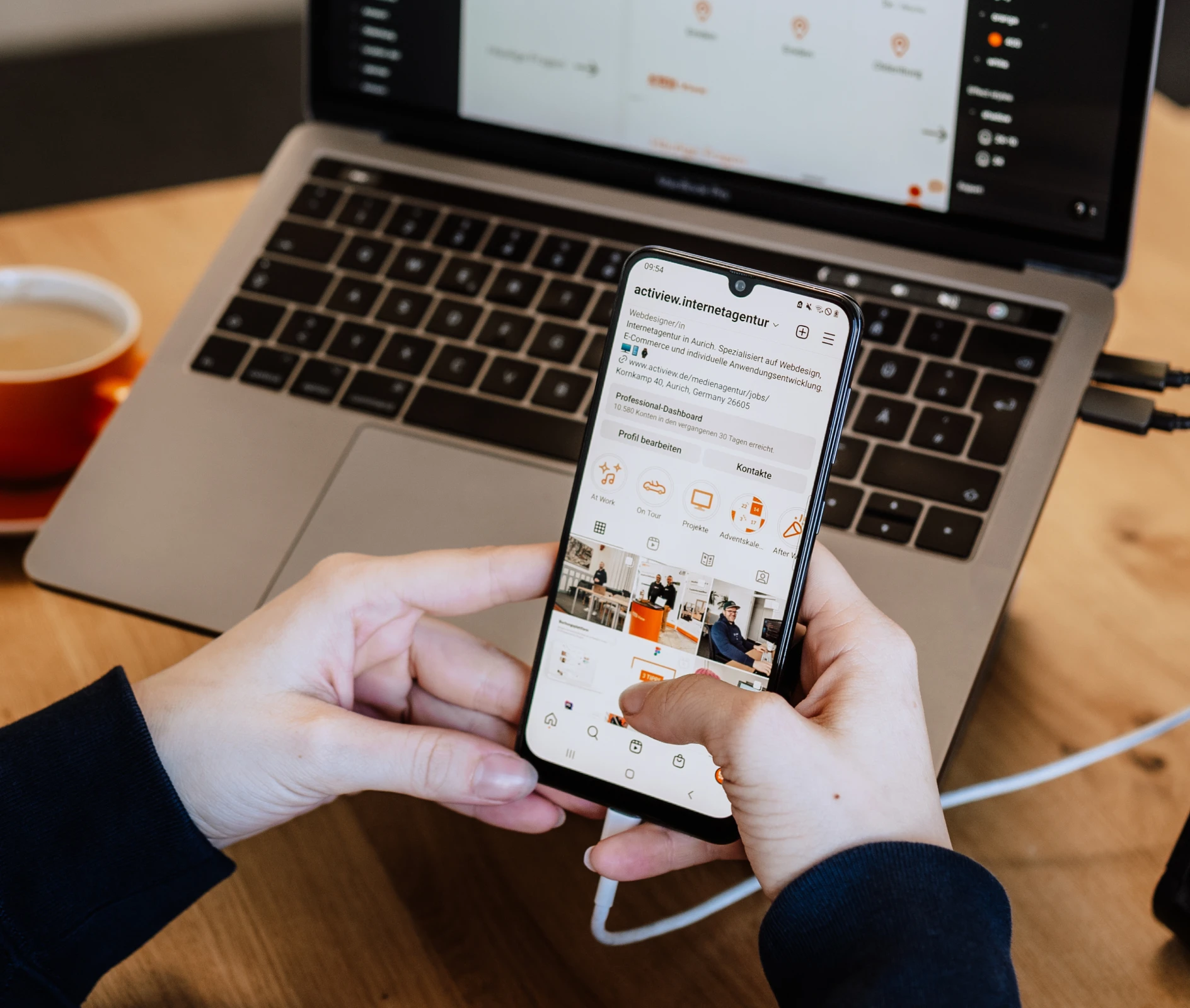 Ein Mitarbeiter überprüft eine Unternehmensseite auf Instagram neben einem geöffneten Laptop mit Projektmanagement-Software und einer Tasse Kaffee